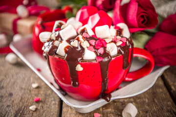 Hot chocolate or coffee latte cup for Valentine day morning. Crazy shake styled hot chocolate or latte with a lot of marshmallow and hearts sugar sprinkles, with gift boxes and roses flowers
