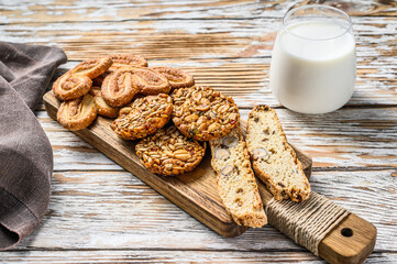 Closeup of a group of assorted cookies with glass of milk. White wooden background. Top view