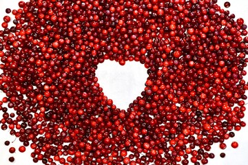 A heart shaped frame made from cranberry berries, on a white background.