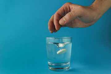 effervescent vitamin C tablet and glass of water on blue background