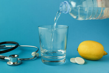 effervescent vitamin C tablet and glass of water on blue background