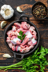 Raw uncooked chicken gizzards, stomach in a pan. Dark wooden background. Top view