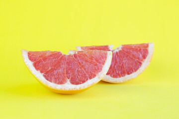 Fototapeta na wymiar Two pieces of grapefruit against yellow background with copy space