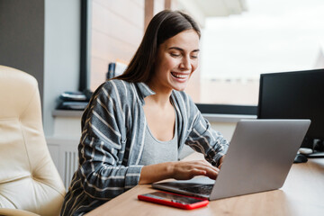 Charming happy woman smiling while working with laptop at home