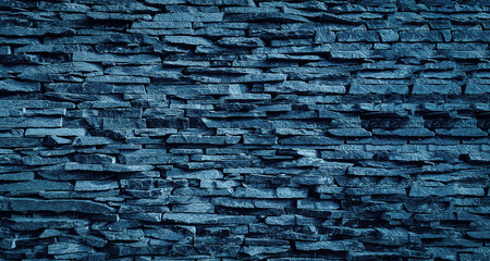 Darfk blue toned abstract natural stone wall as a modern background texture (cinematic color grading)