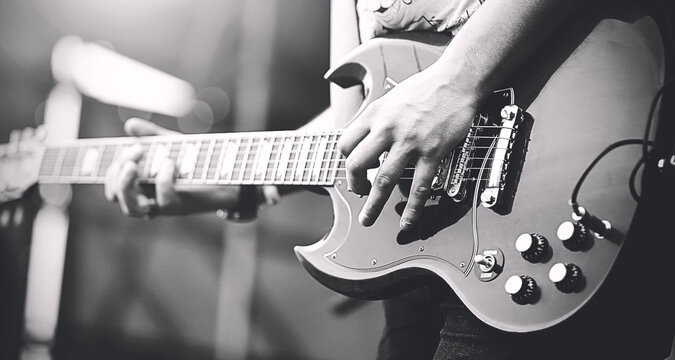Black and white image of professional rock musician playing on electric guitar punk rock concert. Music.