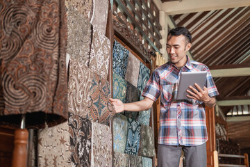 portrait of young men checking stock traditional batik cloth and clothes