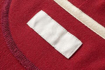 Blank white laundry care clothes label on red fabric texture background