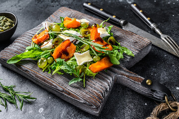 Roasted pumpkin with camembert  cheese and herbs. Healthy vegan food concept. Black background. Top view