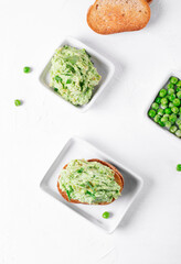 Pate with green peas on toasted bran bread served on the white table with the ingredients. Healthy vegan paste 