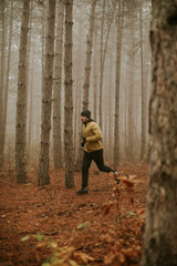 Young man running in autumn forest and exercising for trail run marathon endurance race