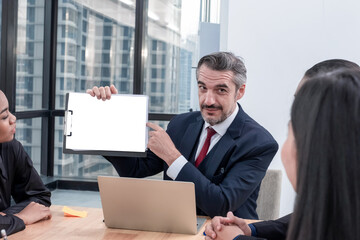 Caucasian CEO bussiness man pointing finger at blank clipboard and looking  to colleague for explain or advise about work or bussiness in meeting room at the office with clipping path on clip board.