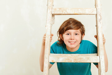 Happy kid looks through ladder. New house for family. Home renovation.