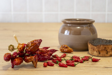 peperoncini piccanti essiccati su tavolo con vaso di coccio scuro