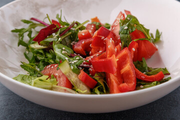 Vegan Spring Salad. Tomato, lettuce, dressing, bell peppers and avocados. Fork with vegetables and salad.