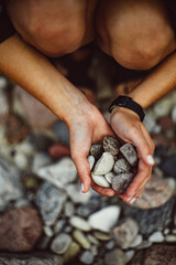 Young woman's hands with a beautiful manicure, hands hold stones, pebbles, small stones