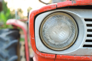 Headlight of the old orange tractor close-up.