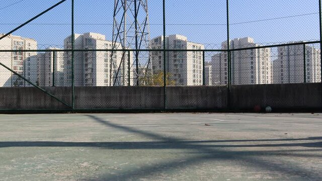 Young man with mask driving with waveboard on asphalt during beautiful day.Apartment buildings in background against blue sky.