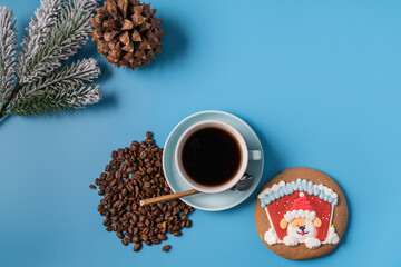 Cup of black coffee , coffee beans and gingerbread on blue background, copy space. Christmas concept.