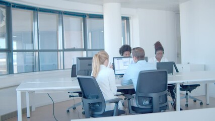 Intern asking mentor about financial data on monitor. Diverse team of financial brokers in headsets. Wide shot. Finance or trading concept - Powered by Adobe