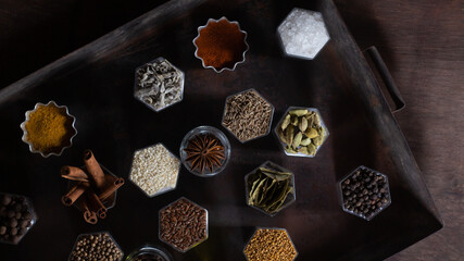 Spices in hexagonal jars appear on a metal rusty baking sheet