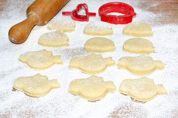 Raw ginger cookies in the shape of birds and hedgehogs, lying on the scattered flour. Selective focus