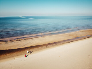 Three people of different ages walked along the sea shore in early spring. The day is sunny and the sea is calm