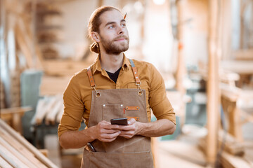 Carpenter with phone in the workshop