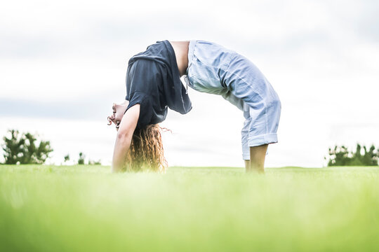 Female acrobat bending over backwards in park