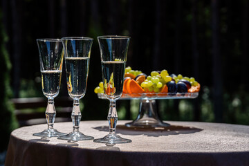 Basket with fruit and glasses with champagne outside.