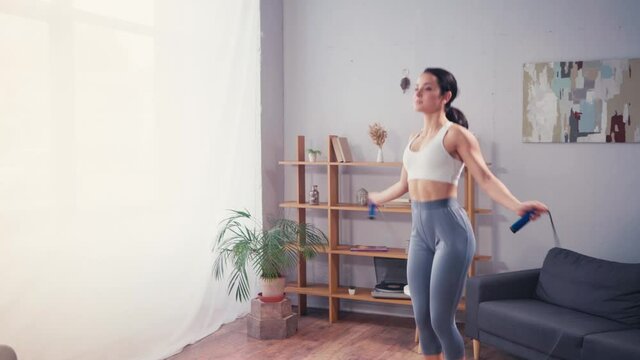 Sportswoman training with skipping rope at home
