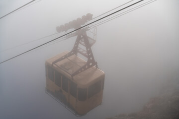 The cable car in Crimea Ai-Petri mountains in thick fog. View from the cliff to the cable car with...