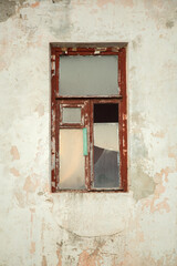 The wall of an old house with a broken window