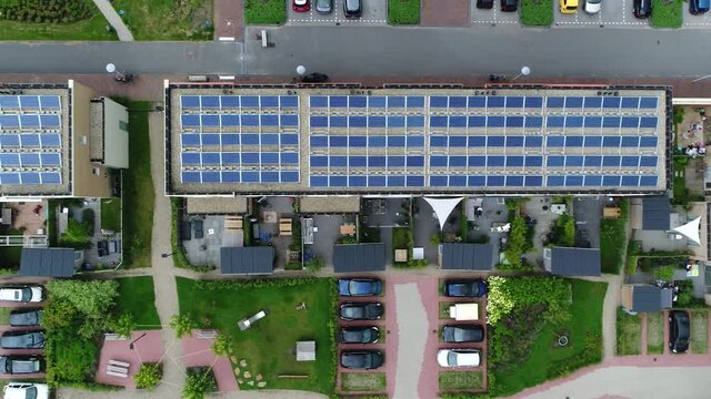 Aerial top down view of new built apartment complex with solar panels installed on the roof from which the photo voltaic cells use sunlight as a source of energy and generate electricity 4k quality