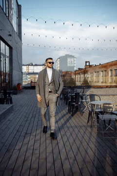Full length body size photo of fashionable man walking outside cafe wearing plaid suit coat sunglass