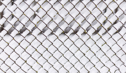 Snow piled on the wires of a chain link fence