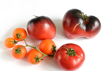 Fresh Yellow Baby plum tomatoes, on branch and dark red tomatos isolated on white background. Large red  burgundy cracked tomato in the shape of a heart. Macro image. Close up.