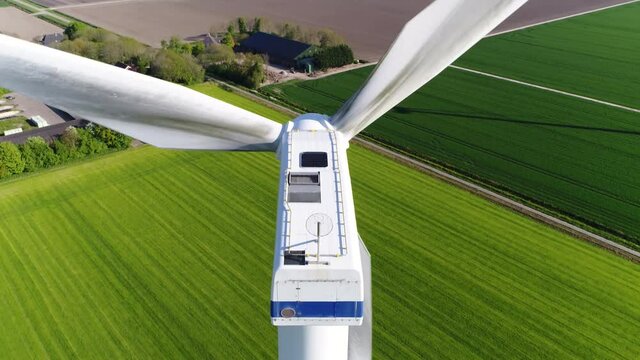 Aerial birds eye view of wind turbine camera panning down the construction is also referred to as a kinetic power converter device located at polder landscape 4k high resolution quality footage