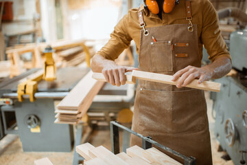 Carpenter folds wooden bars together at the workshop, close-up on hands