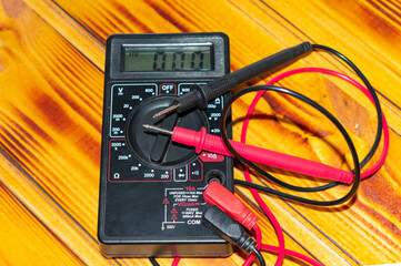 tester, multimeter, electrical measuring device. on a dark wood background.