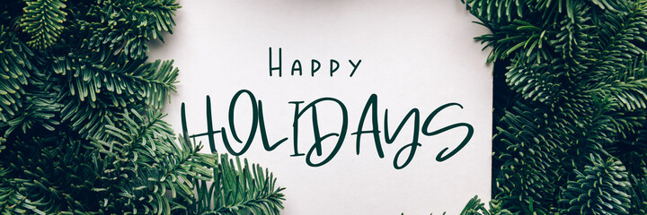 Happy holidays text, card concept. Holiday background with white card in the middle of evergreen tree branches, christmas and festive season idea, minimalistic design, banner size
