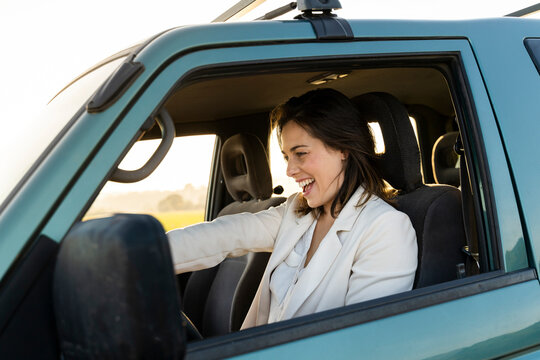 Cheerful young woman driving car during road trip