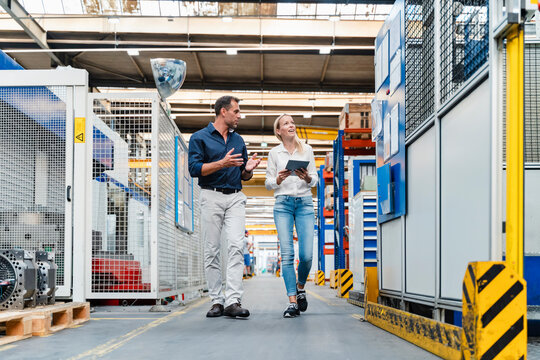 Female and male colleagues discussing while walking in factory