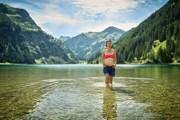 Mature woman knee deep in Vilsalpsee against mountain range on sunny day