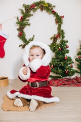 Little cute boy dressed as Santa near little Christmas trees. Christmas mood