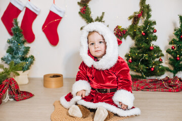 Little cute boy dressed as Santa near little Christmas trees. Christmas mood