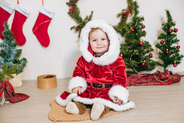 Little cute boy dressed as Santa near little Christmas trees. Christmas mood