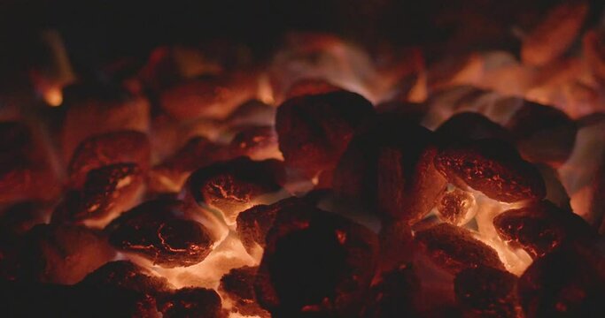 Glowing coals in a campfire. Flames glow from lump charcoal in a steel park grill for barbequing. 