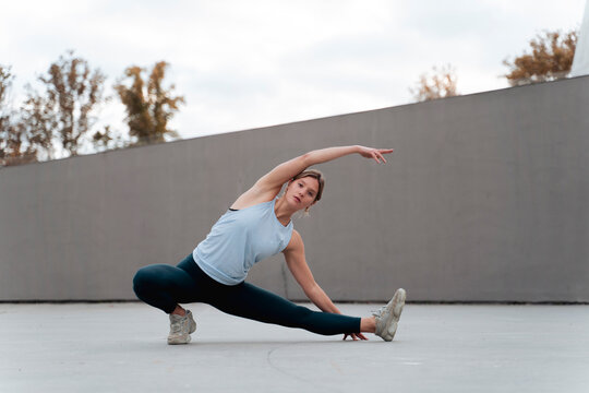 Young woman stretching legs and hands while exercising outdoors