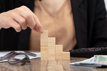 Business woman accounting and banker doing calculations. Concept of success rising with wooden cube.